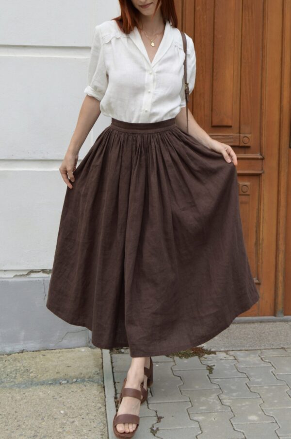 Woman wearing a light linen blouse with a V-neckline, collar, and lace details on the front, elbow-length sleeves.