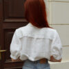 Lydia blouse back slovakmeadows Woman wearing a light linen blouse with a V-neckline, collar, and lace details on the front, elbow-length sleeves.